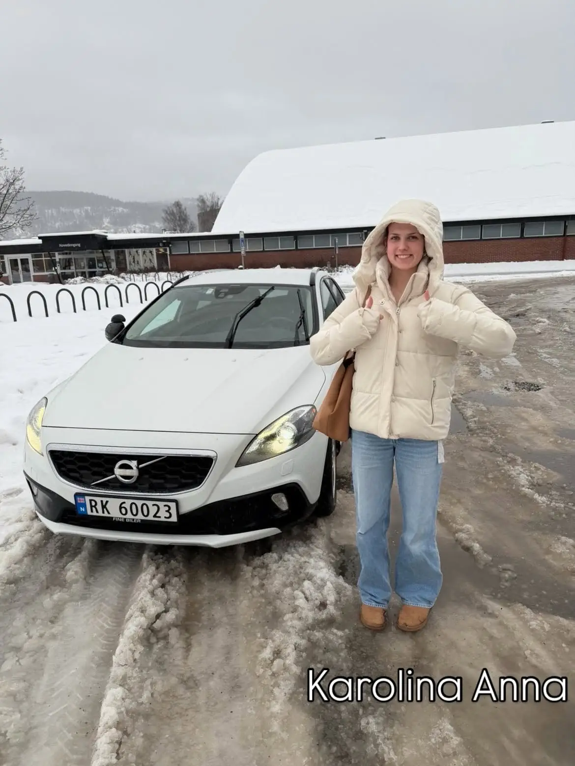 Ny sjåfør med førerkortet i hånda foran en Volvo i snøen