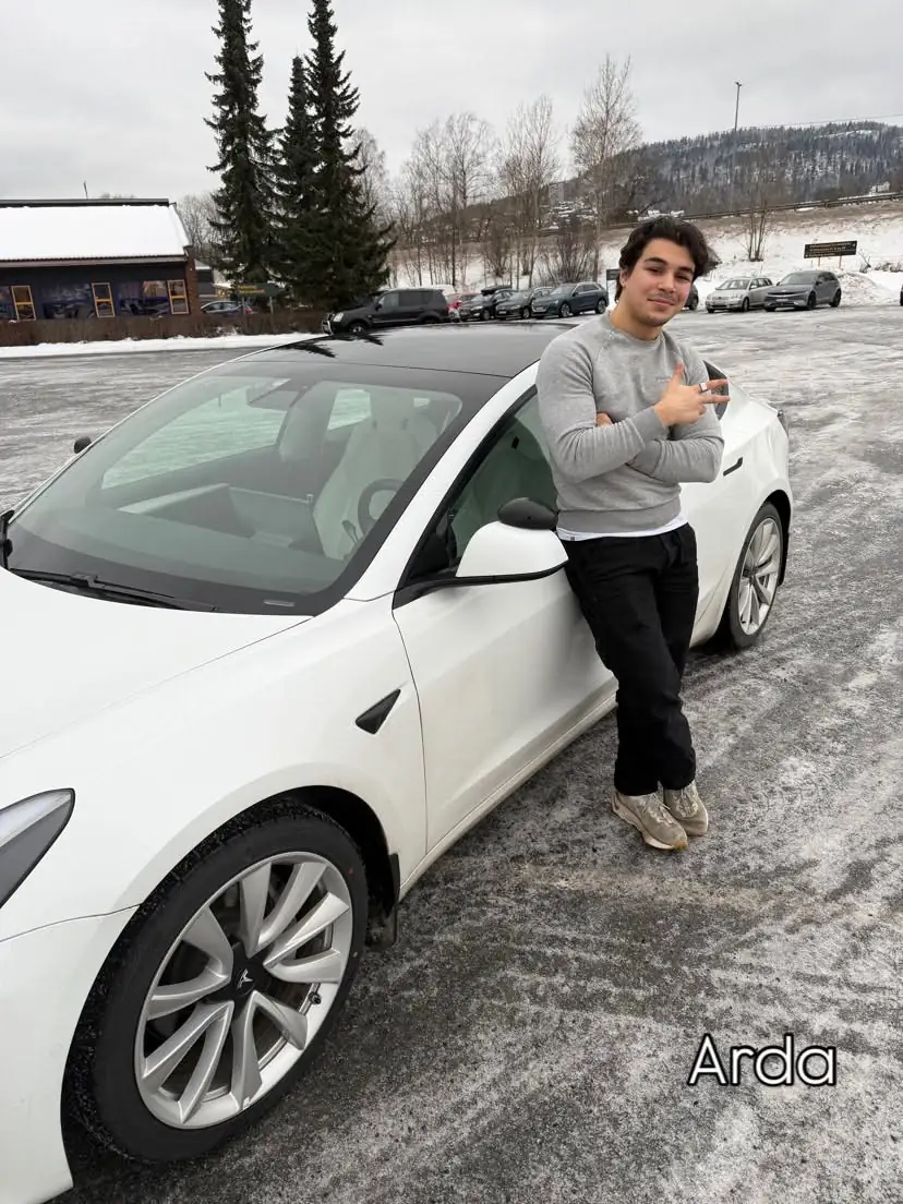 Elev med tommelen opp ved skolens Tesla i snøen