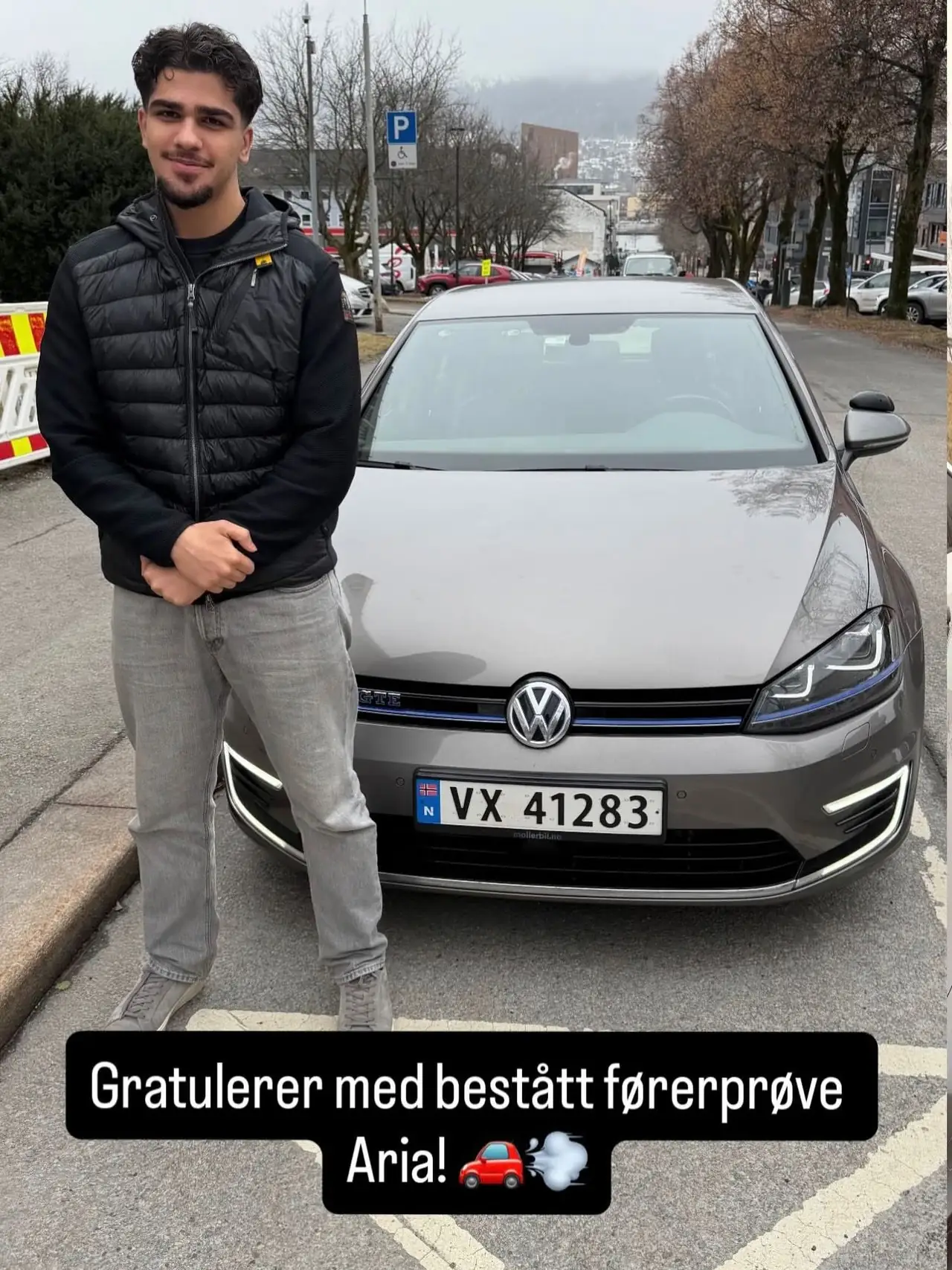 Aria ved skolens Volkswagen Golf etter bestått førerprøve